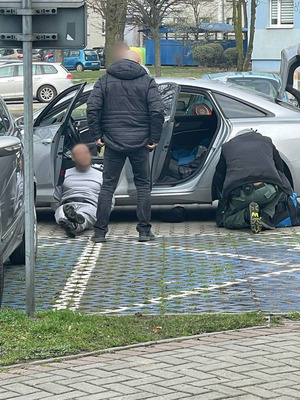 zatrzymany w kajdankach leży oparty o samochód