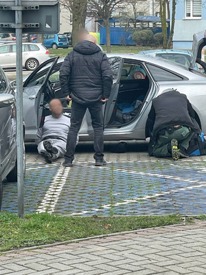 zatrzymany w kajdankach leży oparty o samochód