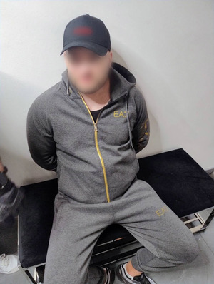 zatrzymany skuty kajdankami z tyłu siedzący na krześle