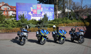 Oznakowane motocykle na tle tablicy z logo Komendy Powiatowej Policji w Bochni