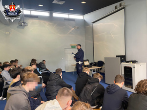 3. Policjant ruchu drogowego trzymający laserowy miernik tłumaczy młodzieży na temat zachowania w czasie kontroli