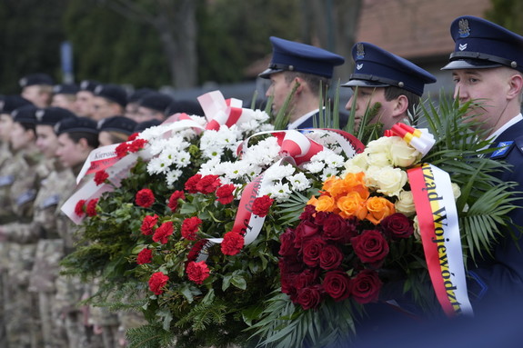 policjanci trzymają w rękach wiązanki kwiatów
