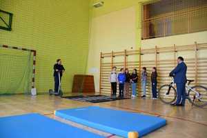 Policjant pokazuje praktyczne zastosowanie przepisów ruchu drogowego uczniom szkoły podstawowej