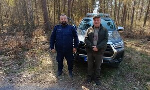 umundurowany policjant KPP Chrzanów ze strażnikiem leśnym pozują przy samochodzie w lesie