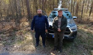 umundurowany policjant KPP Chrzanów ze strażnikiem leśnym pozują przy samochodzie w lesie