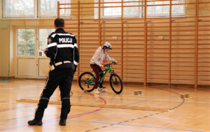 Umundurowany policjant oraz uczeń jadący rowerem