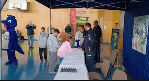 umundurowani policjanci w sali gimnastycznej a przed nimi dzieci