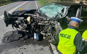 policjant wykonujący oględziny uszkodzonego w wypadku pojazdu