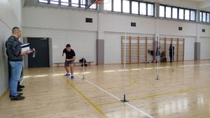 Chłopak w pozycji do biegu przed nim stojące tyczki