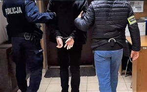 KPP Oświęcim. policjanci prowadzą zatrzymanego który ma założone kajdanki