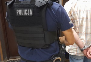 Zatrzymany w kajdankach zapiętych z tyłu obok policjant