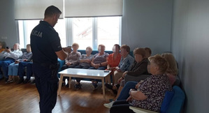 Umundurowany Policjant w pomieszczeniu z seniorami