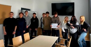 Grupa osób, dziewcząt i chłopców, stojących przodem, po prawej stronie umundurowana policjantka.