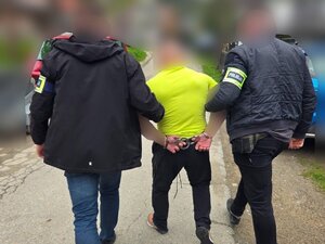 nieumundurowani policjanci prowadzą zatrzymanego