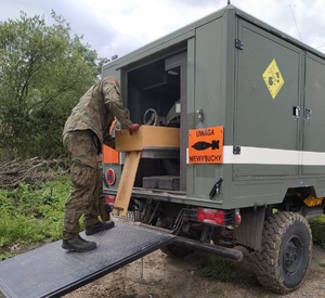 KPP Oświęcim. Saper zabezpiecza niewybuch na samochodzie wojskowym przykład