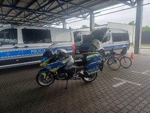 dwa oznakowane radiowozy a przed nimi policyjny motor