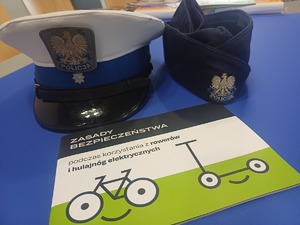 dwie policyjne czapki i poradnik o bezpieczeństiwe