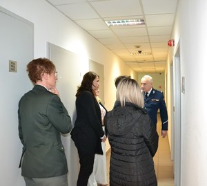 komendant prowadzi gości korytarzem budynku