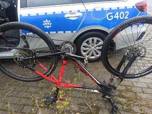 KPP Oświęcim. Obok radiowozu stoi rower odwrócony  kołami do góry numery fabryczne na dolnej części ramy roweru