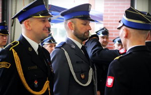 Policjant w mundurze galowym oraz strażacy