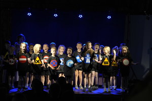 klasa na scenie tańczy w rytm muzyki w podkoszulkach z wydrukowanymi znakami drogowymi