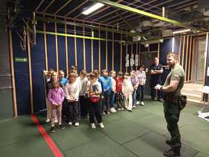 Dzieci na strzelnicy z instruktorem strzelań