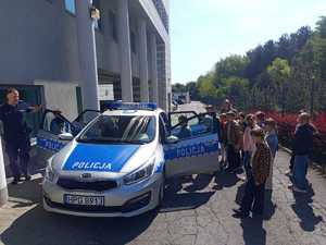 Uczniowie przed budynkiem komendy przy policyjnym radiowozie