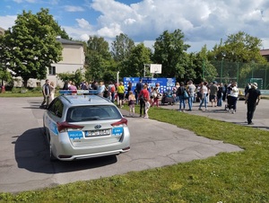 policyjny radiowóz i grupa osób podczas pikniku na terenie przedszkola