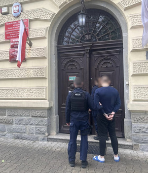 Policjanci z zatrzymanym przed budynkiem prokuratury