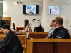 Policjant a w tle zatrzymany mężczyzna