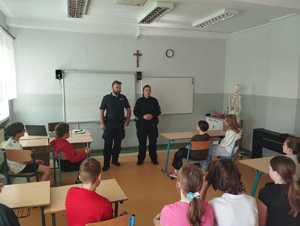 Policjant i policjantka stoją w klasie przed dziećmi.