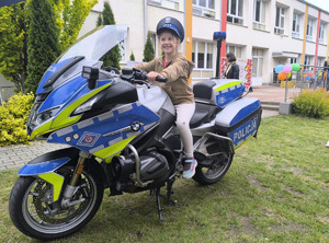 dziewczynka siedząca na motocyklu w policyjnej czapce