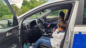 Dziecko siedzi za kierownicą radiowozu.