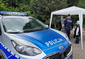 Policjanci pomagają dziecku założyć elementy umundurowania.