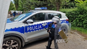 Dziecko z elementami policyjnego umundurowania przy radiowozie.