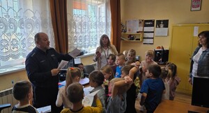 Policjant rozdaje dzieciom kolorowanki.