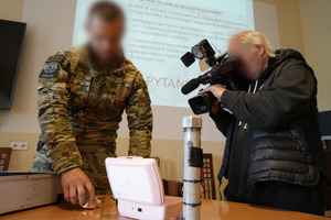 policjant pokazuje atrapę ładunku wybuchowego