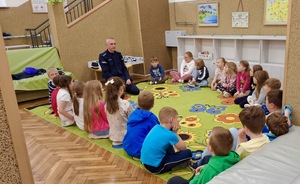 Dzieci siedzą w kółko z Policjantem.