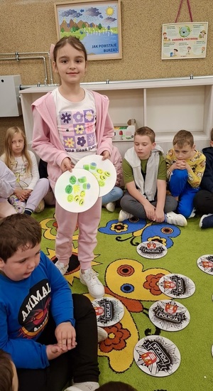 Dziecko trzyma krążki z informacją o odblaskach.