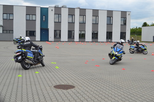 Policjanci na motocyklach objeżdżający przeszkody po okręgu