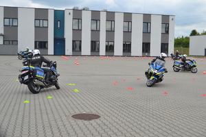 Policjanci na motocyklach objeżdżający przeszkody po okręgu