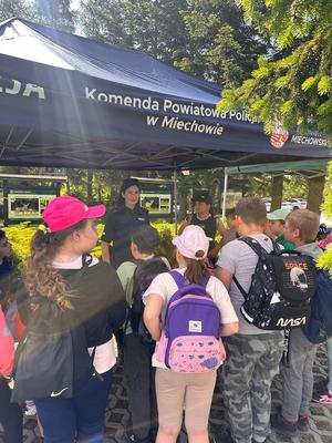 dzieci stoja przy namiocie z policjantką