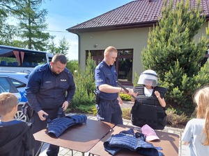 dzielnicowi pomaga załozyć kamizelkę policyjną dziecku