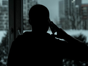 Mężczyzna, na którego pada cień, trzymający telefon komórkowy