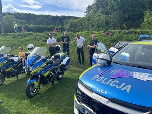 umundurowani policjanci, przed nimi motory policyjne i oznakowany radiowóz