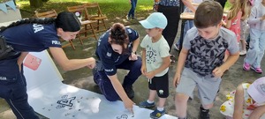 policjantki pomagają dzieciom wklejać literki do elementarza