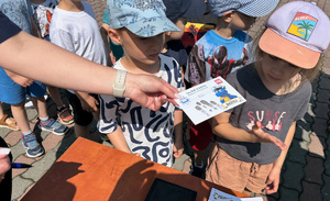 policjantka wręcza dziecku na pamiątkę kartę z jego odbitymi odciskami palców