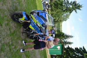 Dziecko siedzące na motocyklu  policyjnym obok mężczyzna stoi z dzieckiem