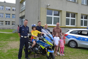 Policjantka, policjanci z innymi osobami przy motocyklu policyjnym