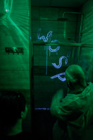 napis WOŚP na płytkach w łazience oświetlony luminolem w ciemności